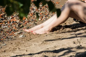 Cute candid girl wearing a skirt sitting on the ground - a sneaky photo with a closeup of her bare feet with pedicure
