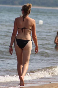 Strawberry blonde sexy mature girl walking the beach in black bikini