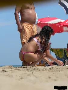 Hot brunette ethnic girl on the beach in a pink thong bikini