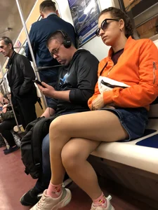 Subway Candid Girl in Denim Shorts and Sneakers Sitting With Crossed Legs in the Train