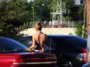 Group of cute girls at a car wash in bikinis and shorts
