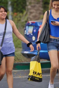 Sexy girl in denim shorts handcuffed to her friend outside