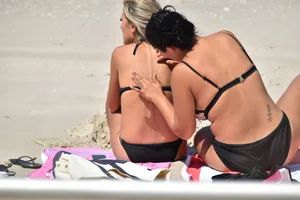 Blonde and brunette on the beach looking sexy in their bikinis