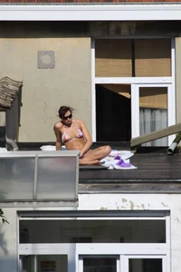 Neighbor on rooftop tanning in bikinis