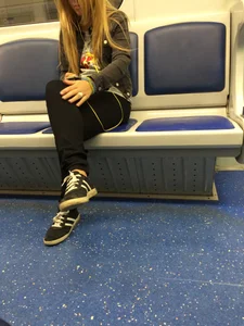 Girl in Tight Pants Sitting in a Subway Train with Her Legs Crossed Candid Photo