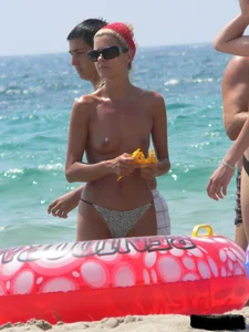 Topless skinny blonde lady in a g-string bikini at the beach