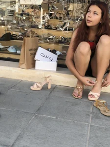 Nice girl in shorts sitting on a step on the street trying on shoes