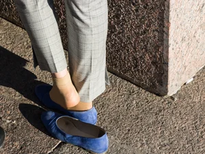 Feet in transparent short socks and flats closeups on the street: candid girl taking off her shoe and plating with her foot in public
