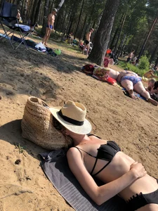 Girl in a Black Swimsuit Lying on a Beach With Her Face Covered With a Hat Creepshots