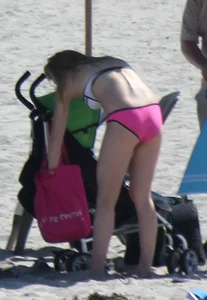 Skinny blonde girl on the beach in her pink and white bikini