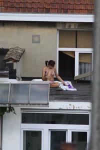 Neighbor on rooftop tanning in bikinis