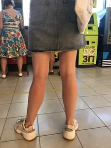 Young Candid Girl With Slim Pale Legs In a Denim Skirt Waiting in the Queue