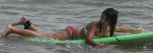 Brunette bikini girl on the beach and surfing in her bikini