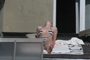 Neighbor on rooftop tanning in bikinis