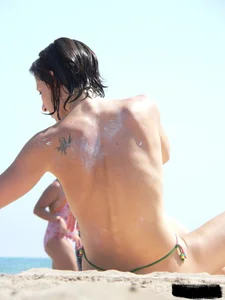 Topless beach milf looking sexy in a tiny g-string bikini