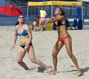 Hot girls playing beach volleyball in bikinis and shorts