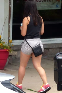 Thick brunette listening to music in shorts