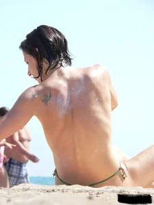 Topless beach milf looking sexy in a tiny g-string bikini
