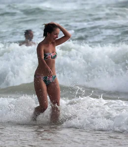 Cute skinny girl in a bikini at the beach playing in the water