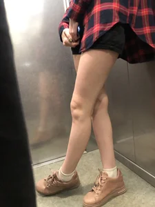 Girl in Shorts And a Shirt Standing With Crossed Legs in the Elevator, then Walking Out