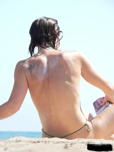 Topless beach milf looking sexy in a tiny g-string bikini
