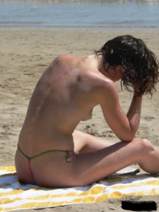 Topless beach milf looking sexy in a tiny g-string bikini