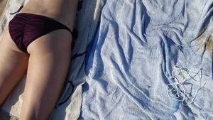 Hot girl laying on the beach in her purple bikini