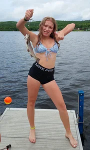 Teen wearing a swimsuit top and spandex shorts showing off a fish