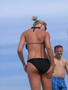 Cute blonde on the beach in a black bikini with nice boobs