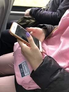 Cute teen girl's manicured hands holding a phone in a public bus creepshots