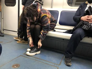 Cute Teen in Black Pantyhose And Sneakers Tying Her Shoelaces in a Subway Train
