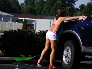 Group of cute girls at a car wash in bikinis and shorts