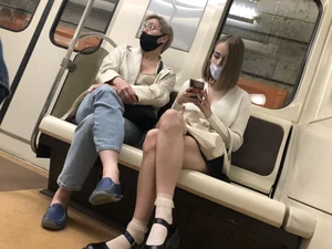 Adorable Young Girl in a Face Mask And White Lace Ruffle Socks Sitting in a Subway Train With Crossed Legs