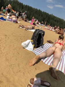 Girl in Red Swimsuit Lying on Her Stomach With Spread Legs on a Beach Creepshots