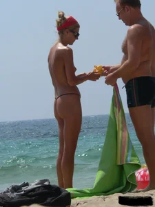 Topless skinny blonde lady in a g-string bikini at the beach