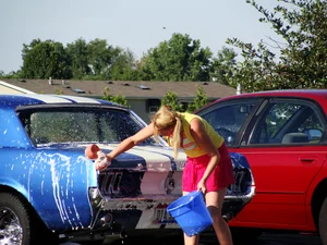 Group of cute girls at a car wash in bikinis and shorts