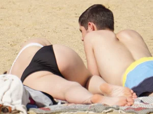 Sexy girl on the beach laying out and bending over in her bikini