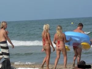 Sexy mom and daughter in red thongs at the beach