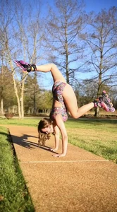 Non-candid gymnast teen showing off her stretch while wearing rollerblades and a leotard in the park