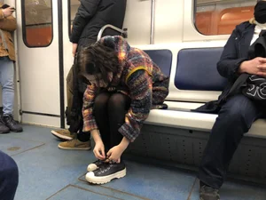 Cute Teen in Black Pantyhose And Sneakers Tying Her Shoelaces in a Subway Train