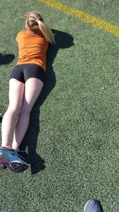 Girl in Spandex Mini Shorts Lying on Grass on Her Stomach With Crossed Legs