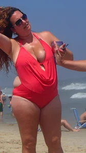 Thick lady on the beach with big boobs in a red swimsuit