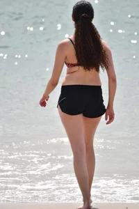 Brunette girl in black shorts and bikini top on the beach