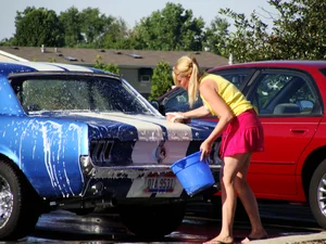 Group of cute girls at a car wash in bikinis and shorts