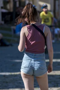 Sexy brunette chick with glasses in denim overalls showing her cheeks