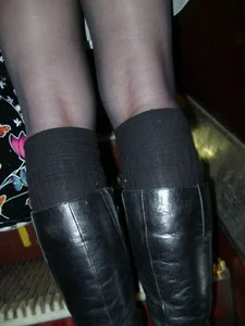 Closeup of hot legs in black pantyhose and knee-high boots on subway escalator