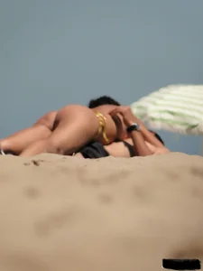 Topless lady on the beach in a gold thong with a nice ass