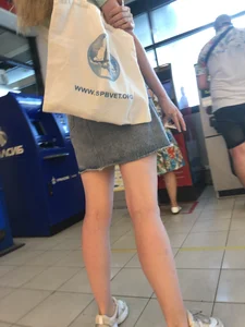 Young Candid Girl With Slim Pale Legs In a Denim Skirt Waiting in the Queue