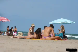 2 topless girls at the beach in thongs