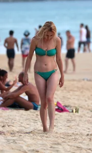 Sexy brunette in thong bikini and blonde friend in green bikini at the beach